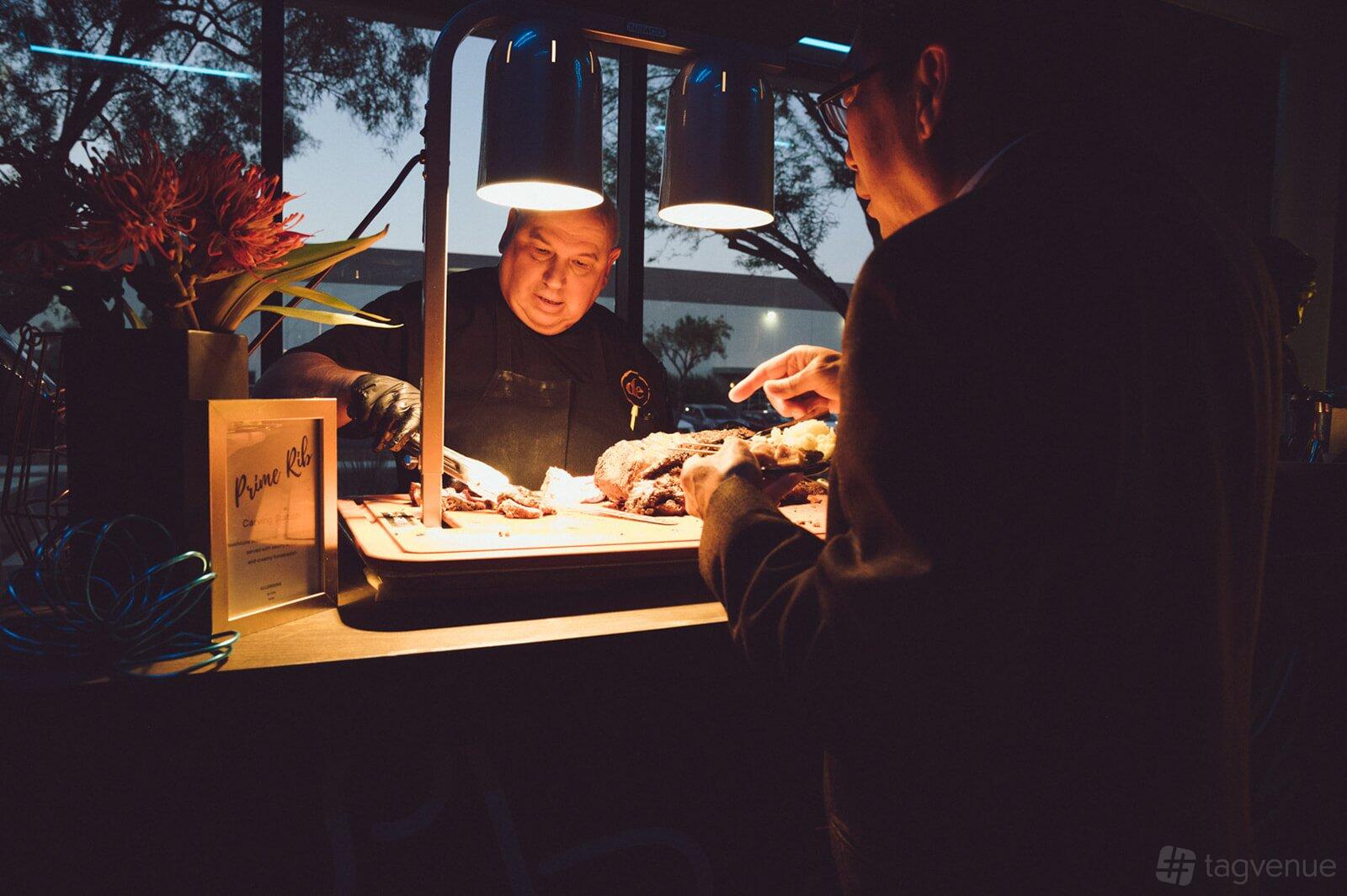 A catering station with a chef carving roast beef under heat lamps at StarBase Las Vegas.