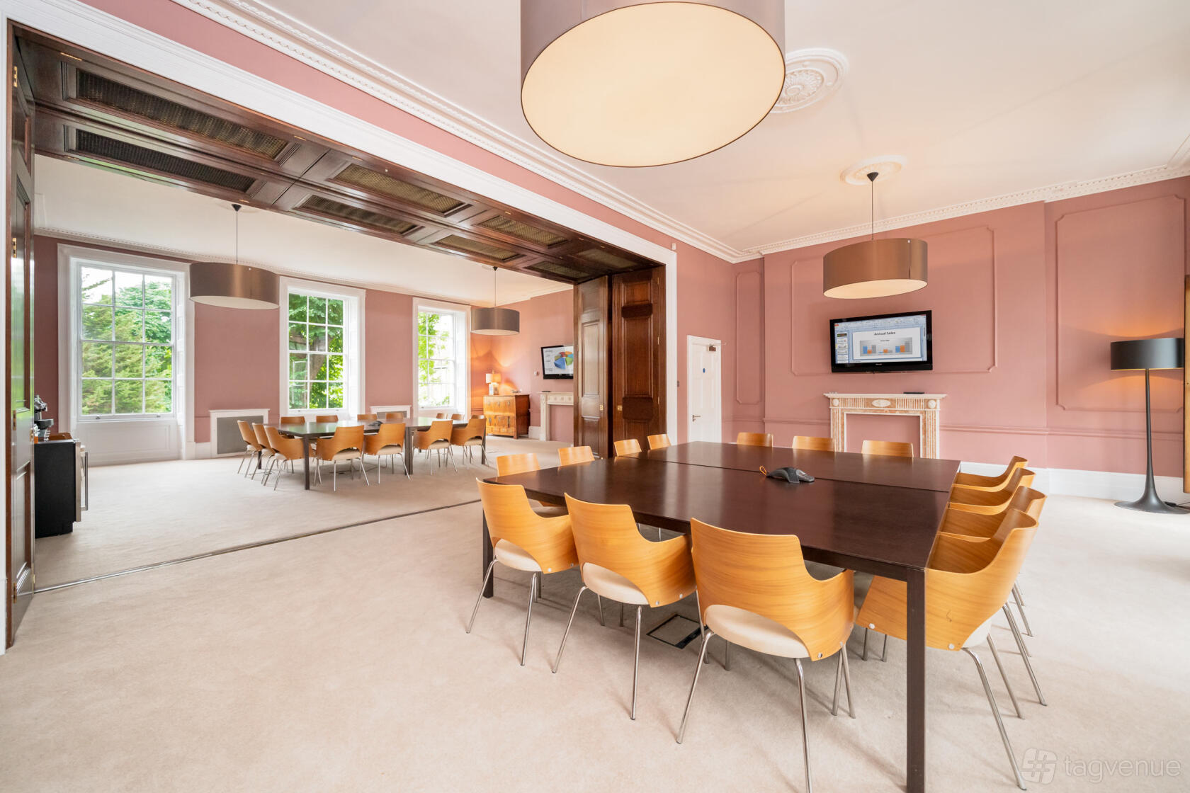 A meeting centre with large windows, wooden chairs around tables, and wall-mounted screens at Russell Square.
