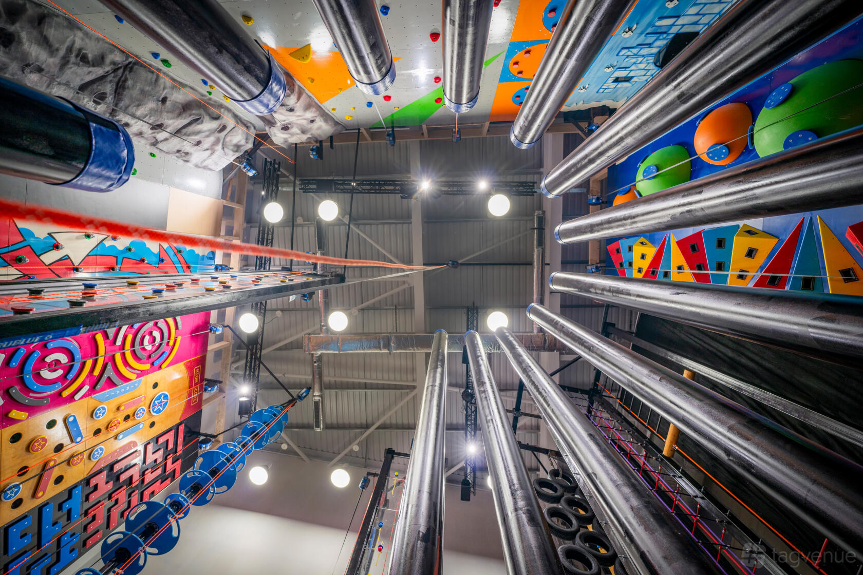 An adventure event space with colorful climbing walls, vertical metal poles, and bright overhead lighting at The Light Redhill.