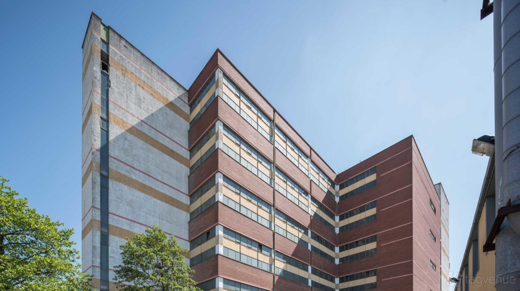 A multi-story red brick building with horizontal stripe accents and large windows at Shannon Studios.