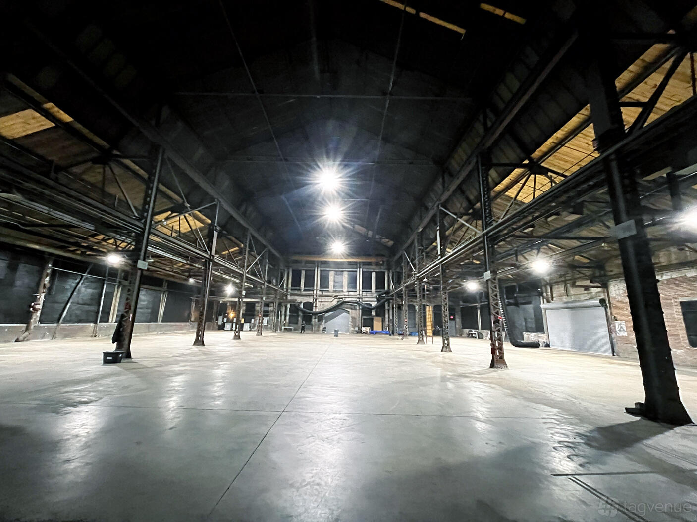 A warehouse with high arched ceilings, exposed steel beams, and concrete floors at Pullman Yards.