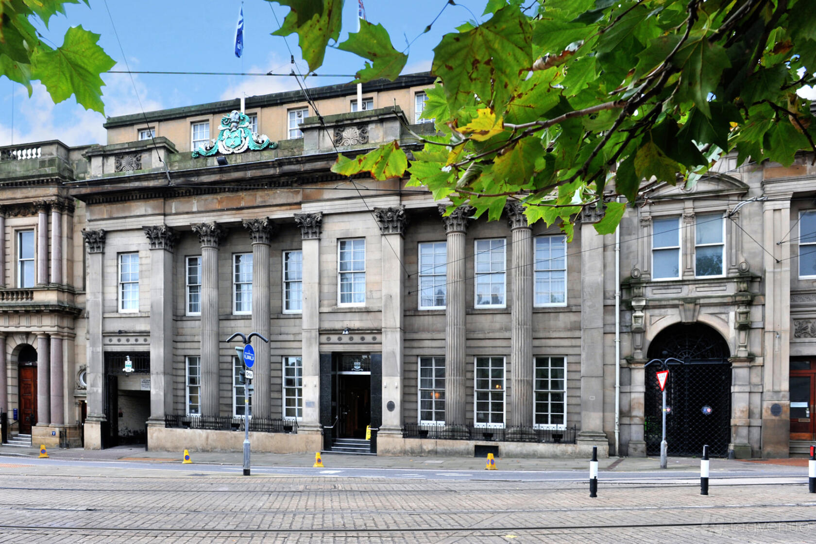 A historic building with grand stone columns, large windows, and ornate crest at Cutlers’ Hall Hospitality.
