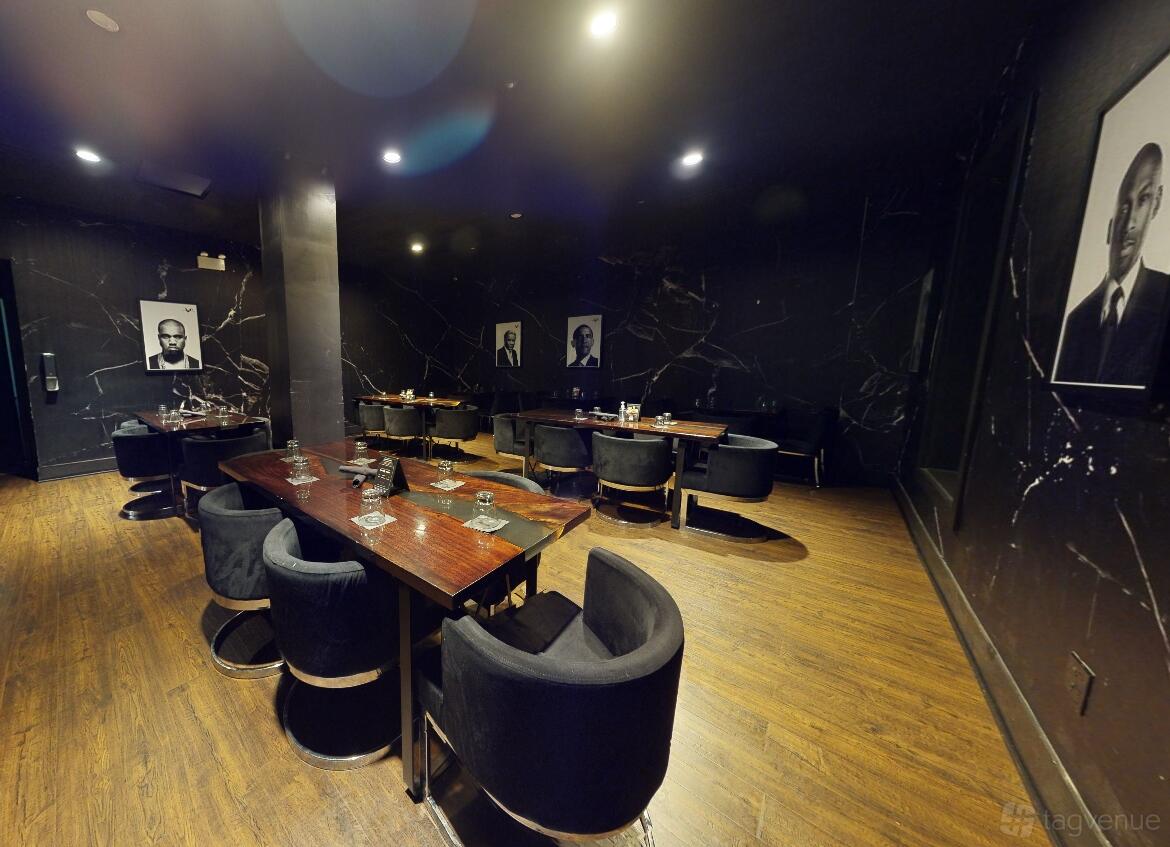 A restaurant lounge with dark marble walls, wood flooring, and black velvet chairs at Kitchen + Kocktails Chicago.