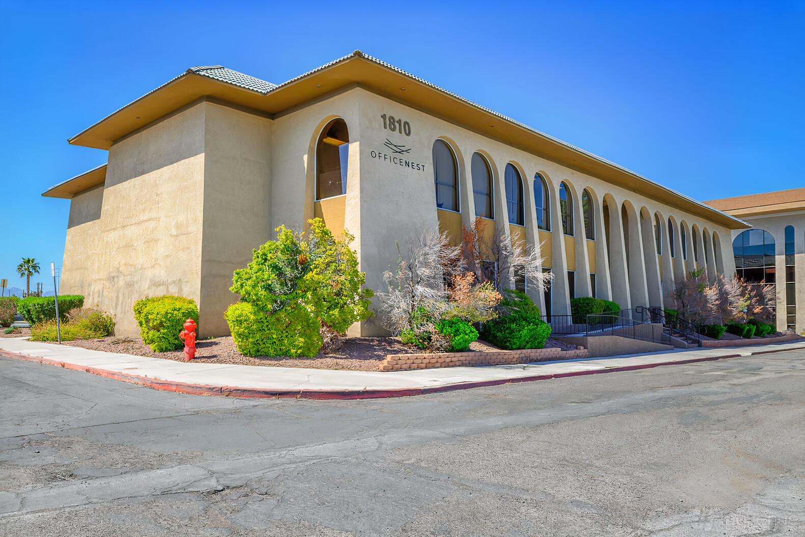 A meeting centre with arched windows, tan façade, and landscaped shrubs at OFFICENEST - LAS VEGAS.