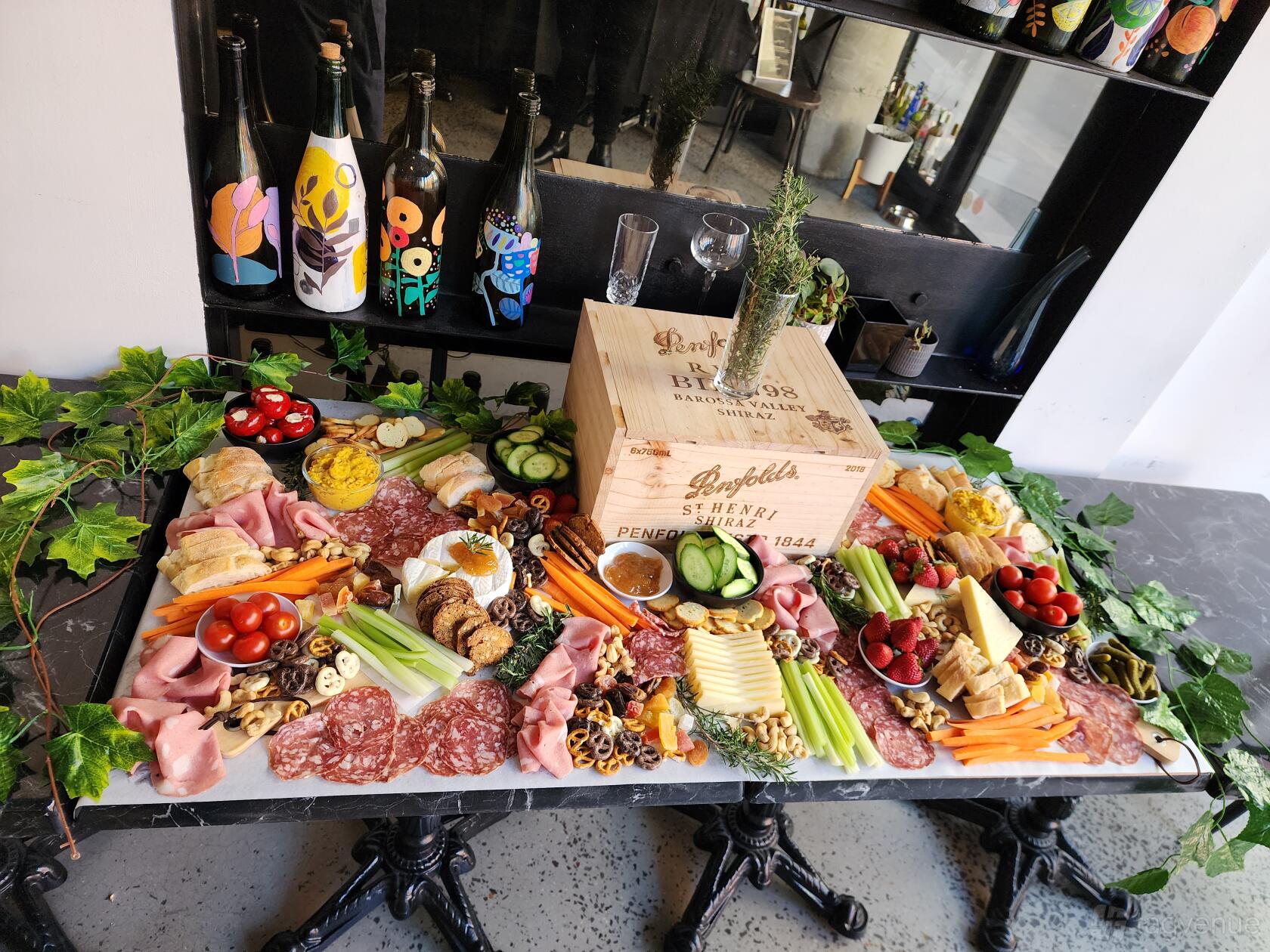 A bar with a marble table topped with charcuterie, cheeses, fruits, and wine bottles at Ruelle Wine Bar.