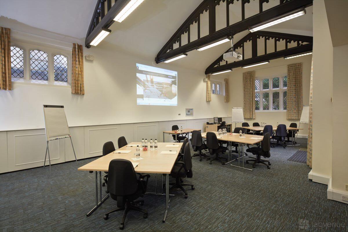 A meeting room with high vaulted ceilings, arched windows, and modular tables with chairs at Ashridge House.