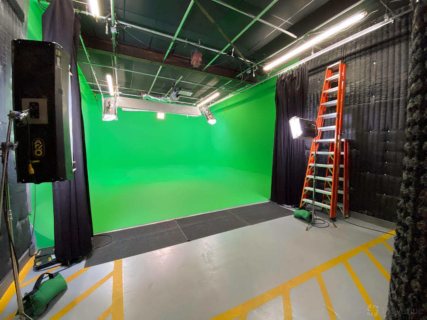 A photo studio with a full green screen backdrop, studio lighting, and a red ladder at The Dreaming Tree.