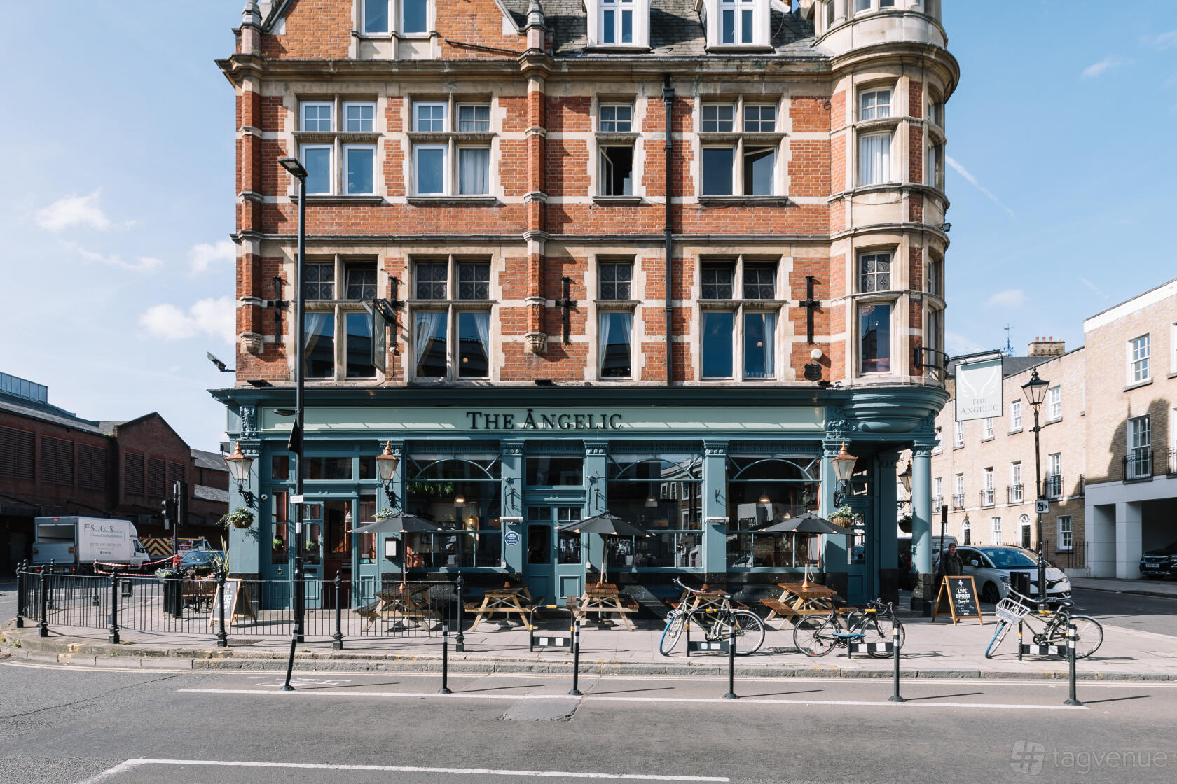 A pub with outdoor wooden benches, large windows, and a traditional brick facade at The Angelic.