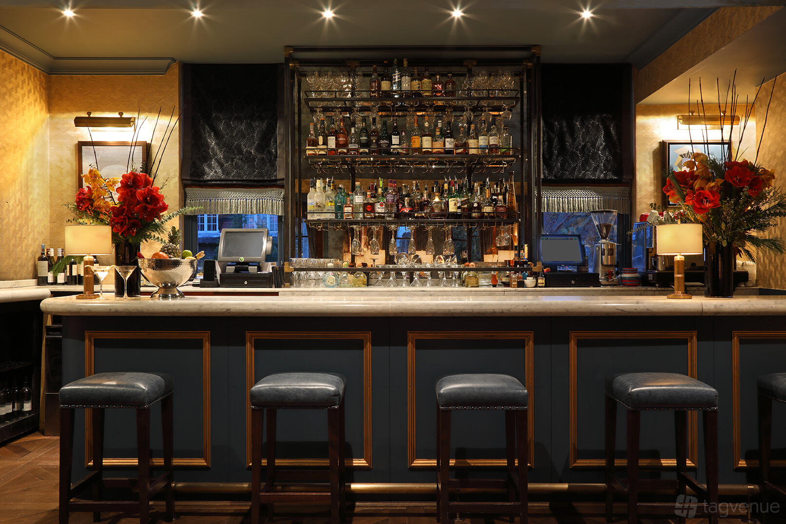 An event space with a marble-topped bar, backlit shelves of spirits, and upholstered stools at Albert's at Beaufort House.