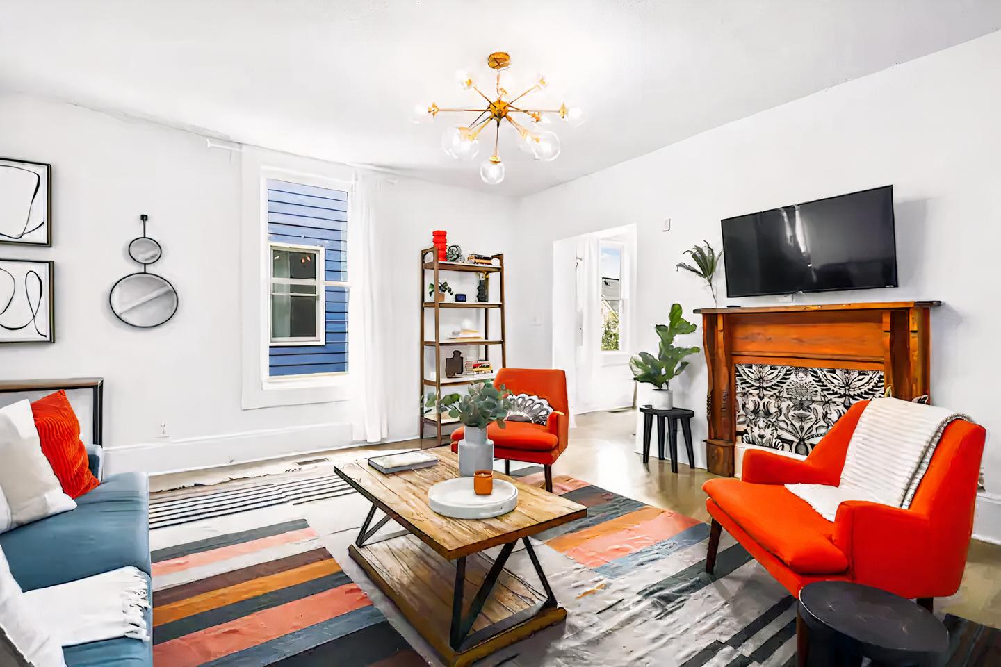 A house living room with colorful armchairs, patterned rug, wall art, and a fireplace at 'Timeless Boho' Home.