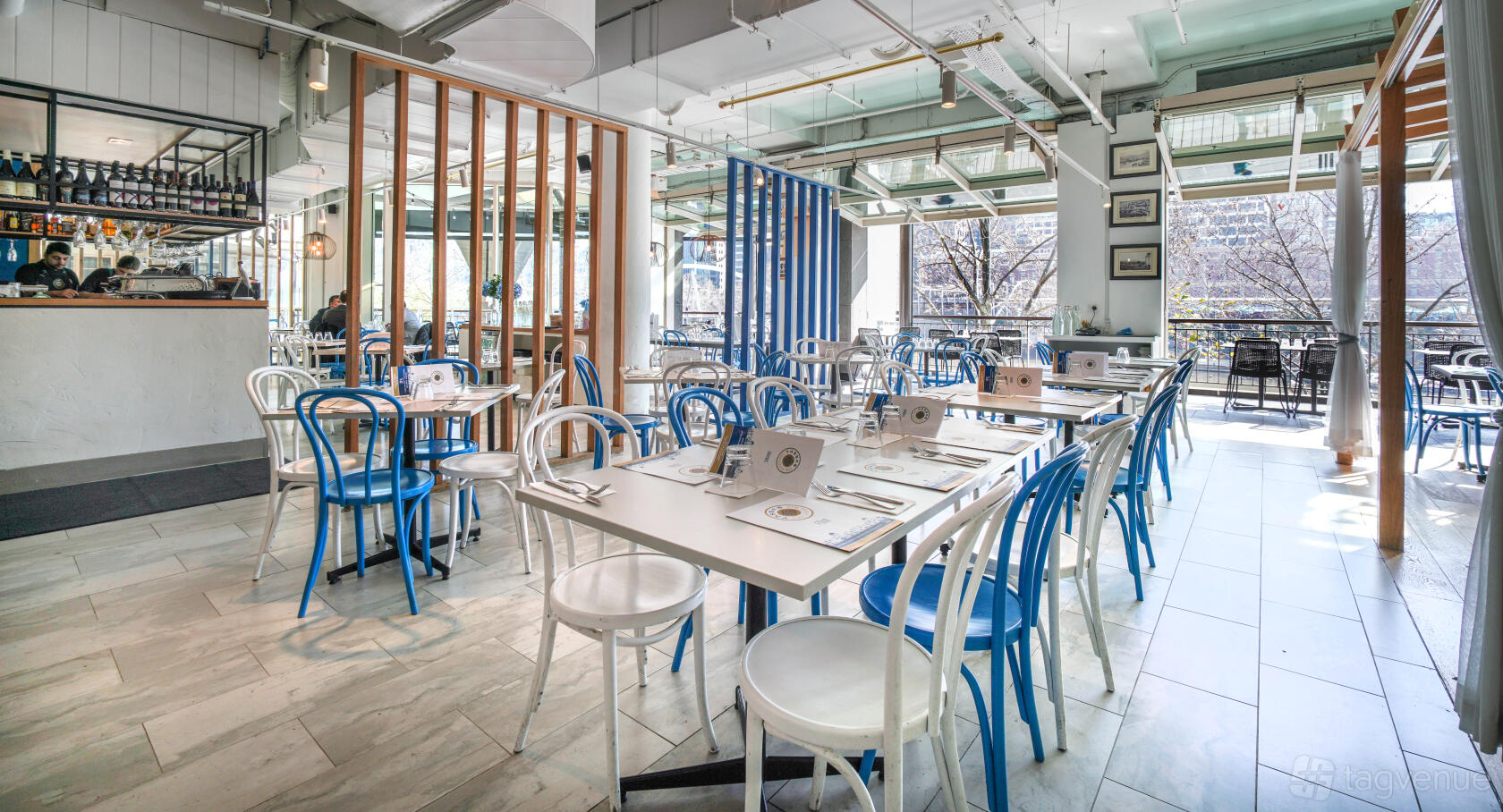 A restaurant with white and blue chairs, marble tile flooring, and large windows at YASSAS – The Greek Way - Southbank.