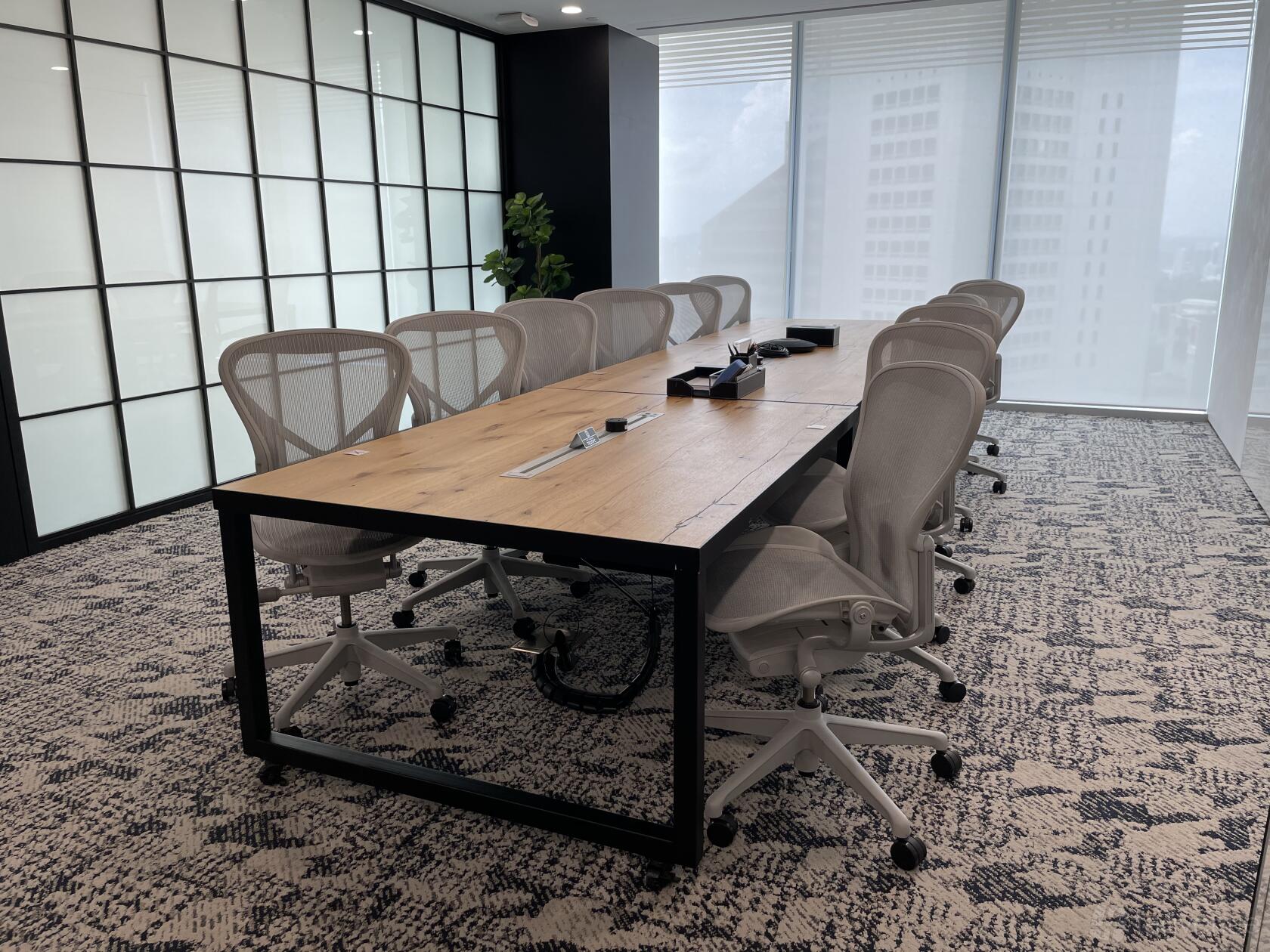 A meeting room with a long wooden conference table, ergonomic chairs, and floor-to-ceiling windows at Ocean Financial Centre.
