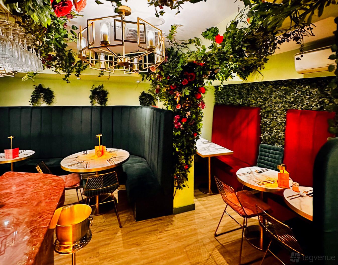 An event space in a restaurant with velvet banquette seating, marble tables, and greenery at Sannio Italian Restaurant & Cocktail Bar.