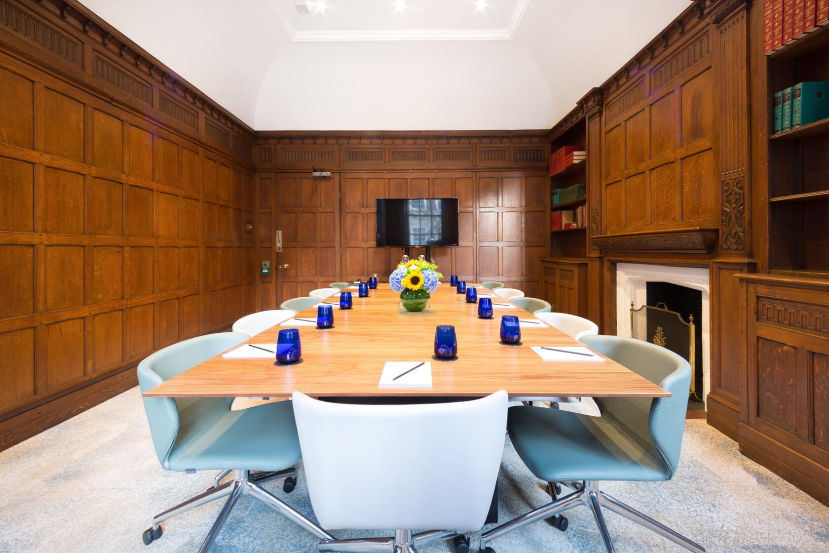 A meeting room with wood-paneled walls, a long conference table, and pastel chairs at Landmark: Marylebone, London.