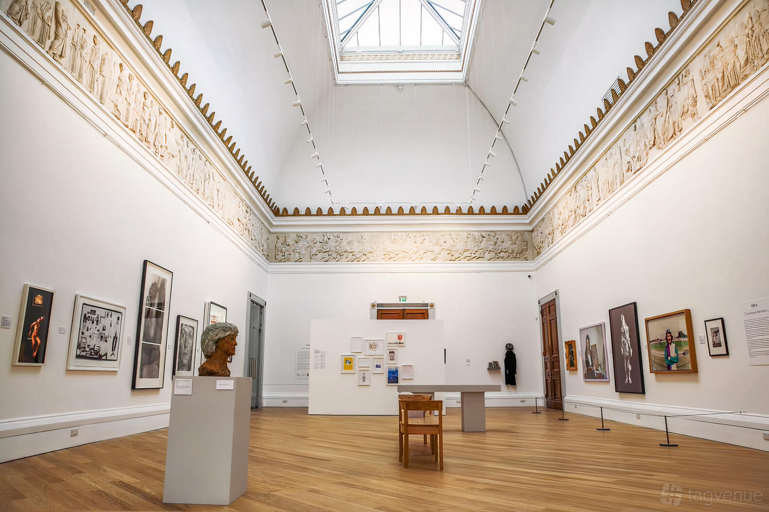 A gallery with high ceilings, skylight, ornate frieze, and art displays at Royal West Of England Academy.