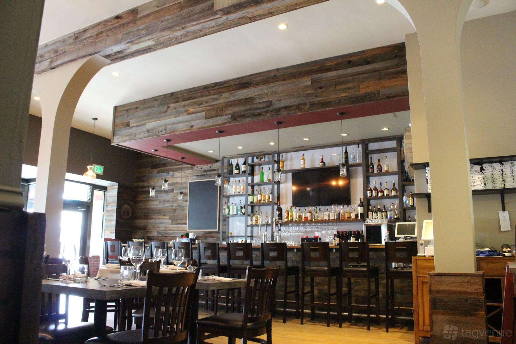 A restaurant interior with a long wooden bar, shelves of liquor bottles, and rustic wood-paneled walls at Farm and Vine.