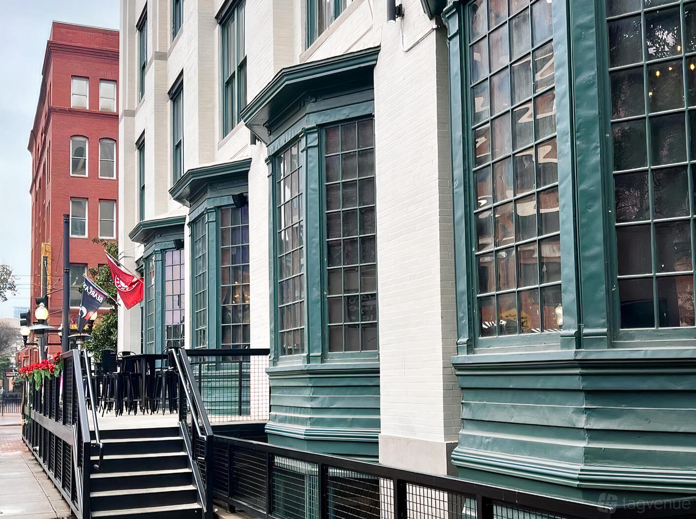 A restaurant with large bay windows, green trim, and outdoor tables along a city sidewalk at Chet's.
