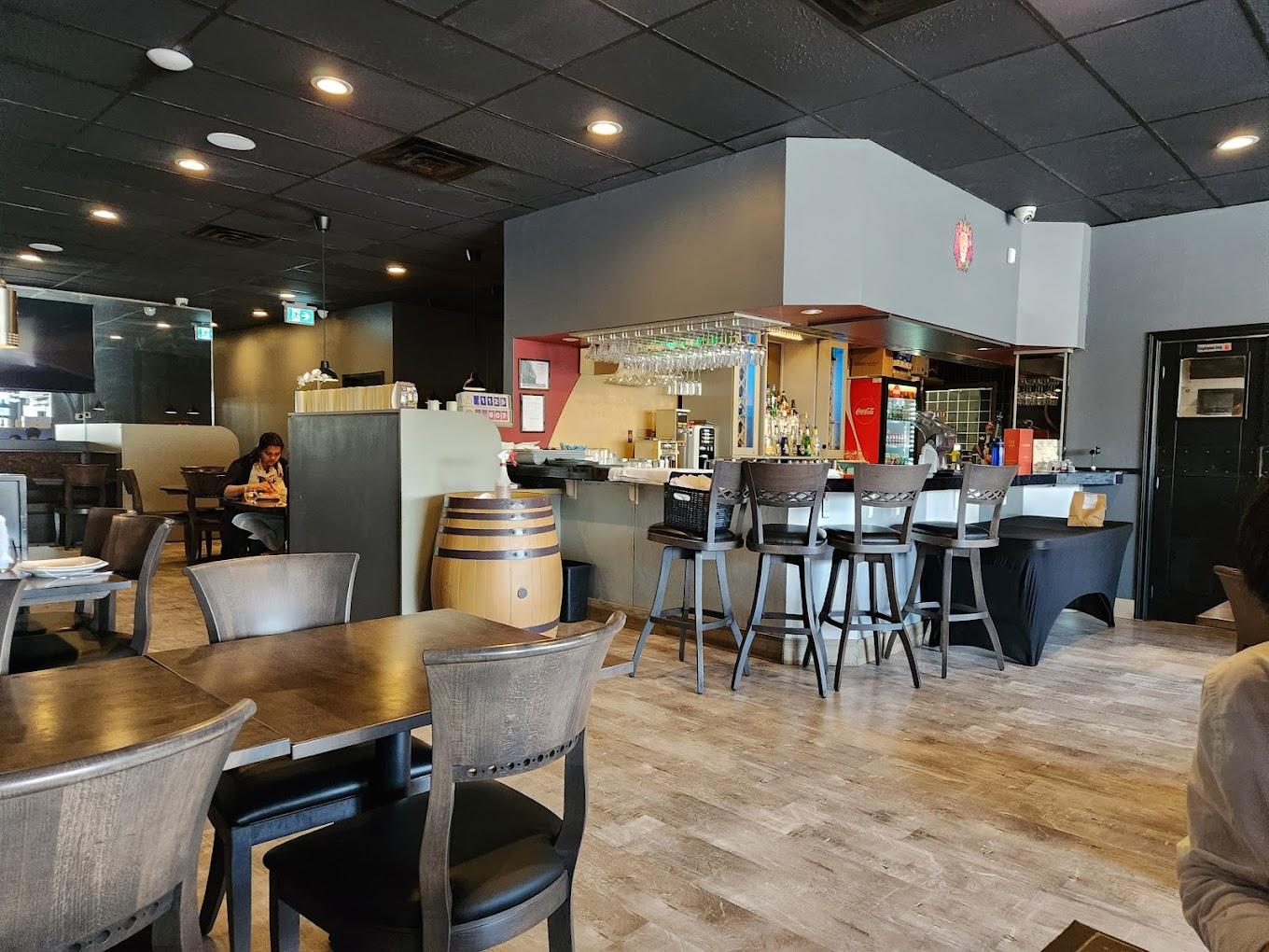 A restaurant with wood flooring, dark wooden tables, and a corner bar with glassware at Oh Bombay - Oakville.