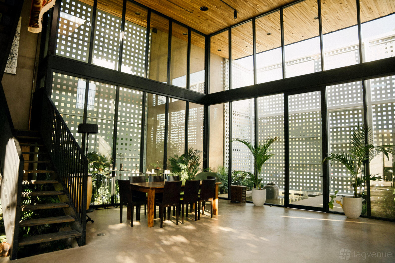 A country house with floor-to-ceiling windows, potted plants, and a wooden dining table at Casa Nueva Verdugo.