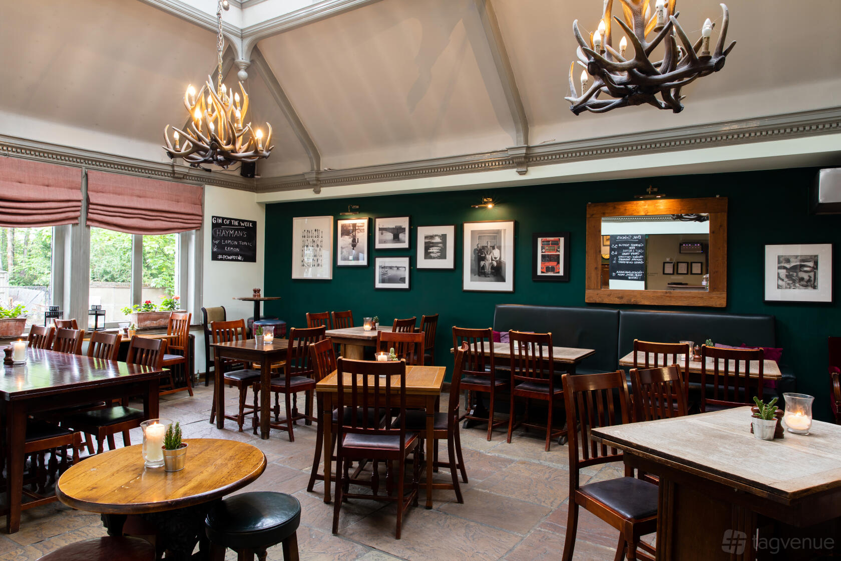 A pub dining area with antler chandeliers, framed photographs, and wooden tables and chairs at The Prince of Wales.