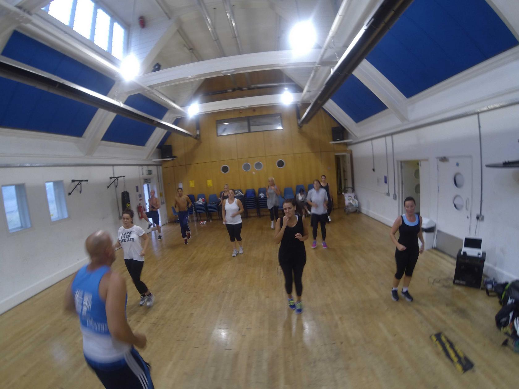 A dance studio with a polished wooden floor, high ceilings, and mirrored wall at Harrow Club W10.