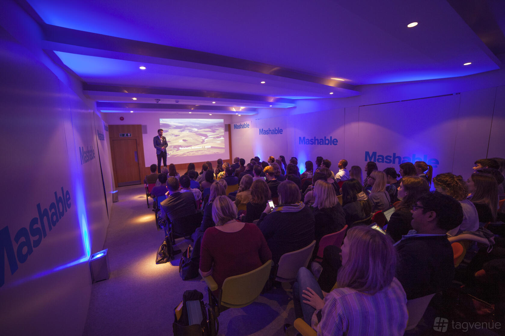 An auditorium with tiered seating, blue ambient lighting, and a presentation screen at Whitechapel Gallery.