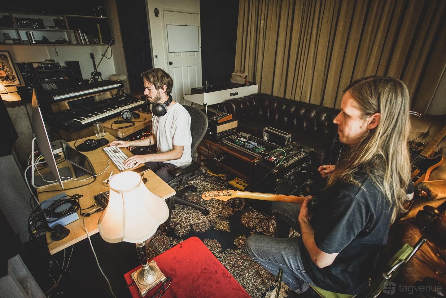 A recording studio with audio equipment, a mixing desk, instruments, and a leather couch at Elusive Creative.
