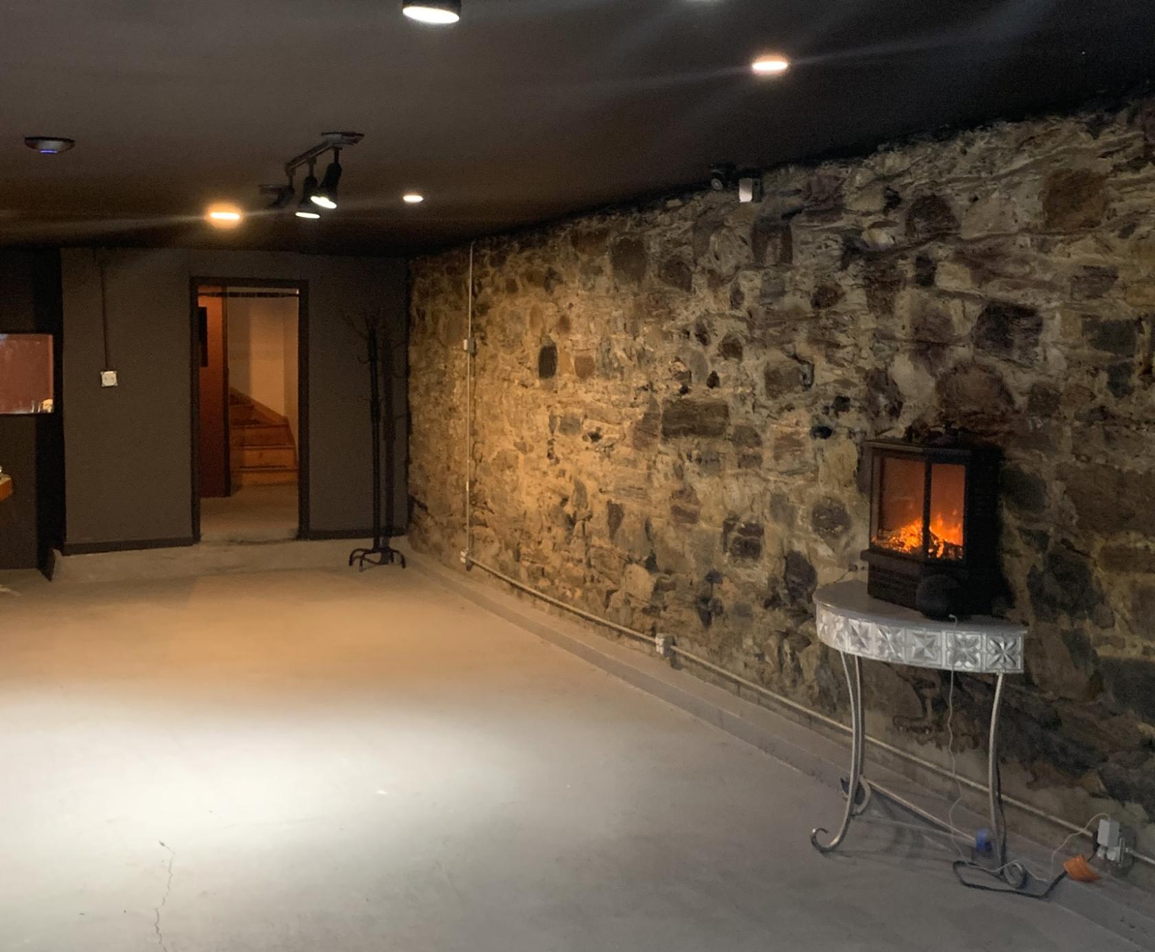 An event venue with exposed stone walls, a faux fireplace, and industrial lighting at H I D D E N.