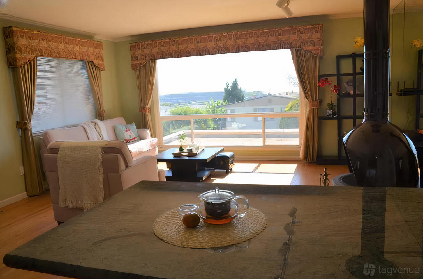 A house living room with large picture windows, light wood floors, a sofa, and views of the bay at Golden Gate and Bay Bridge View House.