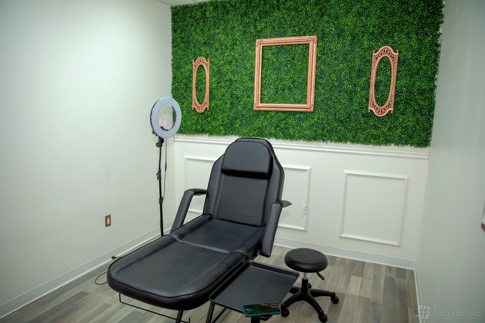 A photo studio room with a black reclining chair, ring light, and green accent wall at Eighty Five 87 Studios.