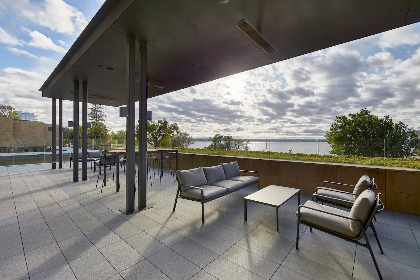 A hotel terrace with outdoor lounge seating, high tables, and views of the river at Wonil Hotel Perth - Handwritten Collection.