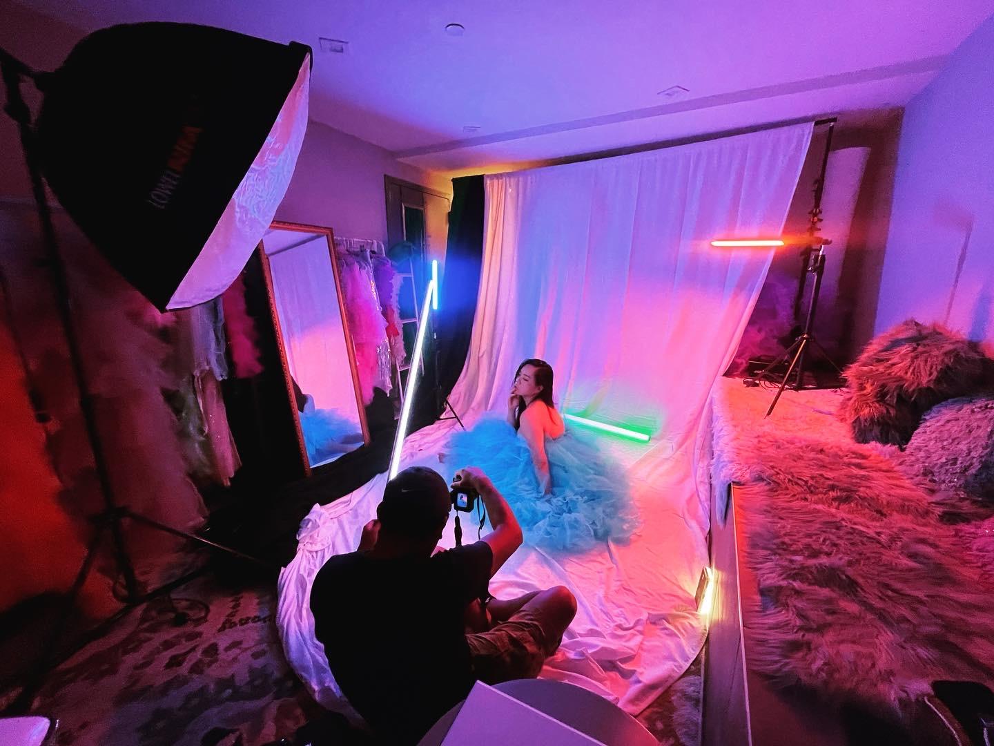 A photo studio with colorful LED lighting, a backdrop, and a photographer capturing a subject at Art Lights Mini Photo Studio.