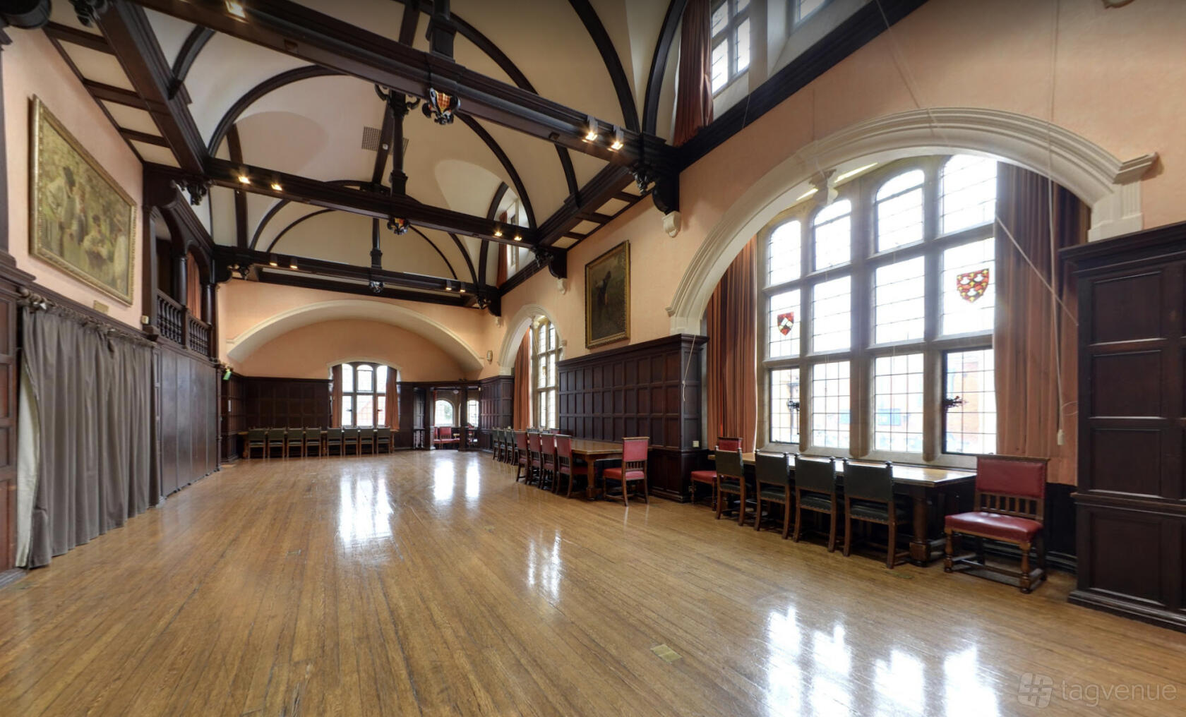 A historic hall with arched beamed ceilings, tall leaded windows, and polished wood floors at Oxford Town Hall.
