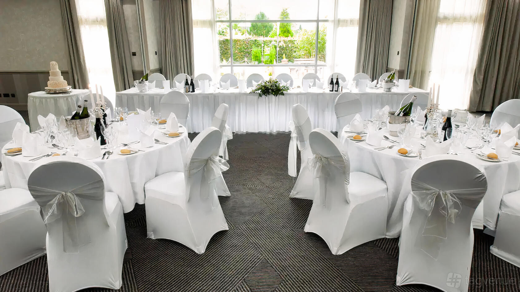 A function room with large windows, round tables set with white linens, and banquet chairs at DoubleTree Glasgow Strathclyde.