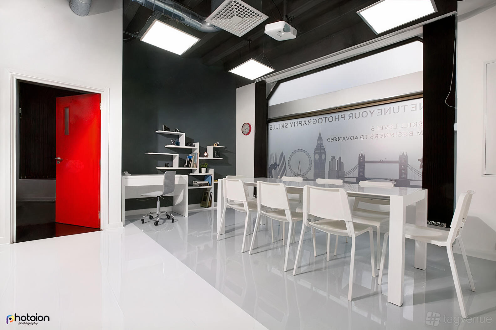 A photo studio with glossy white floors, minimalist white tables and chairs, and large wall graphics at Photoion.
