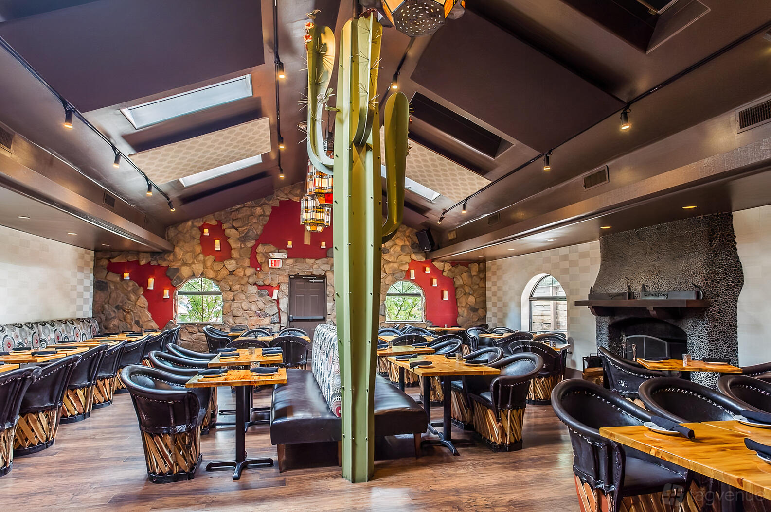 A restaurant dining room with stone accent walls, skylights, wooden tables, and black leather chairs at Coyote Crossing.