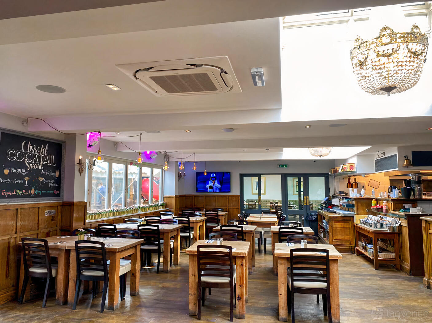 A pub dining area with wooden tables and chairs, chalkboard menu, and a chandelier at Clissold Arms.