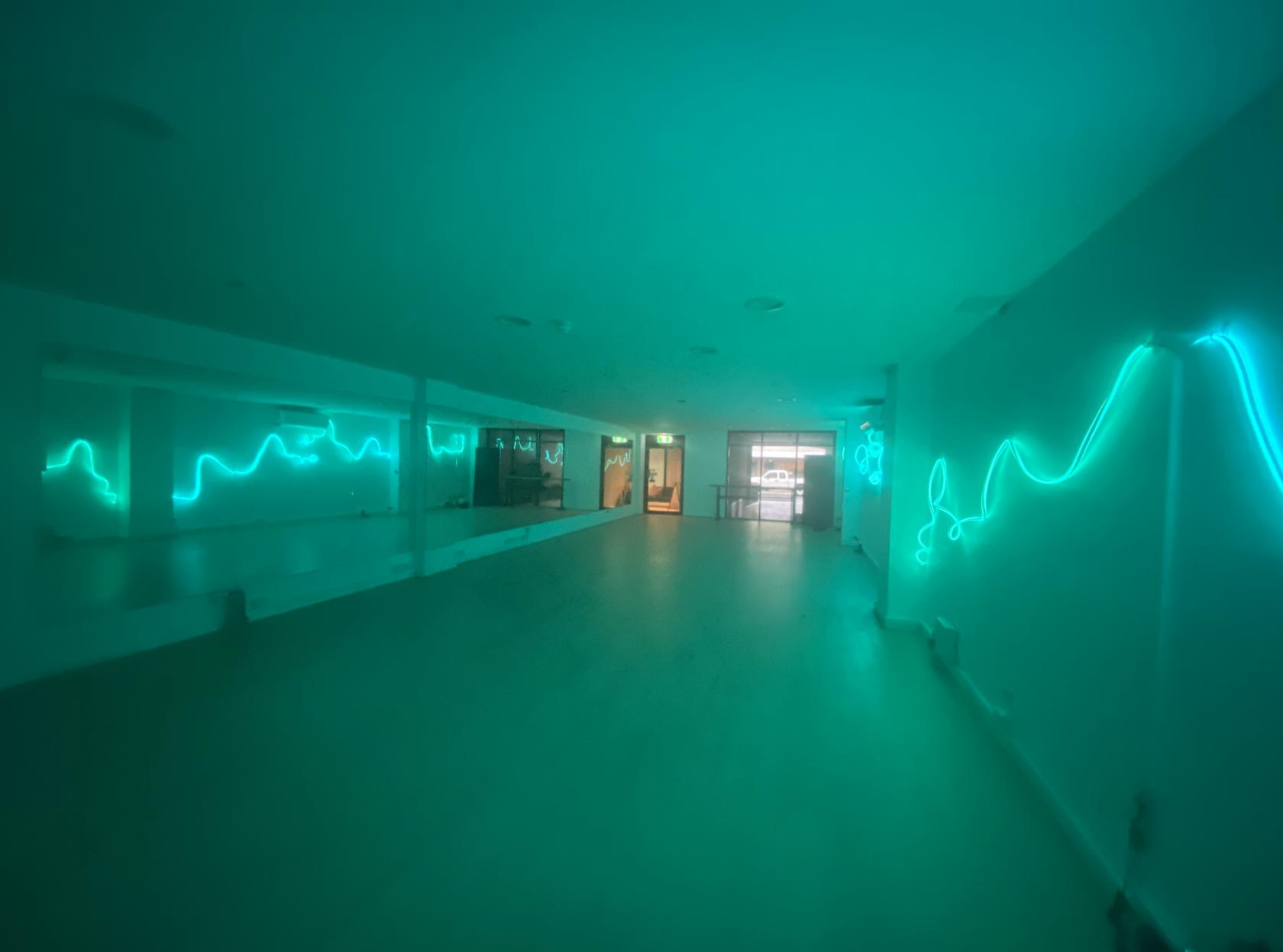 An event space with mirrored walls and teal neon light accents at Elevate Studios.