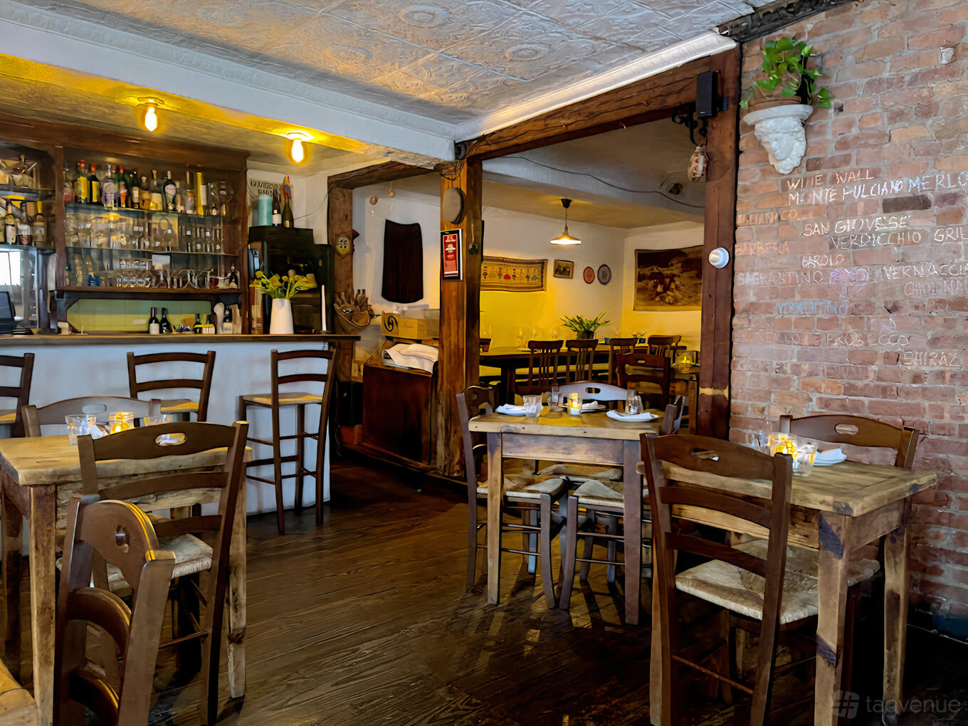 A restaurant with rustic wooden tables, exposed brick walls, and candlelit place settings at DOC Winebar.