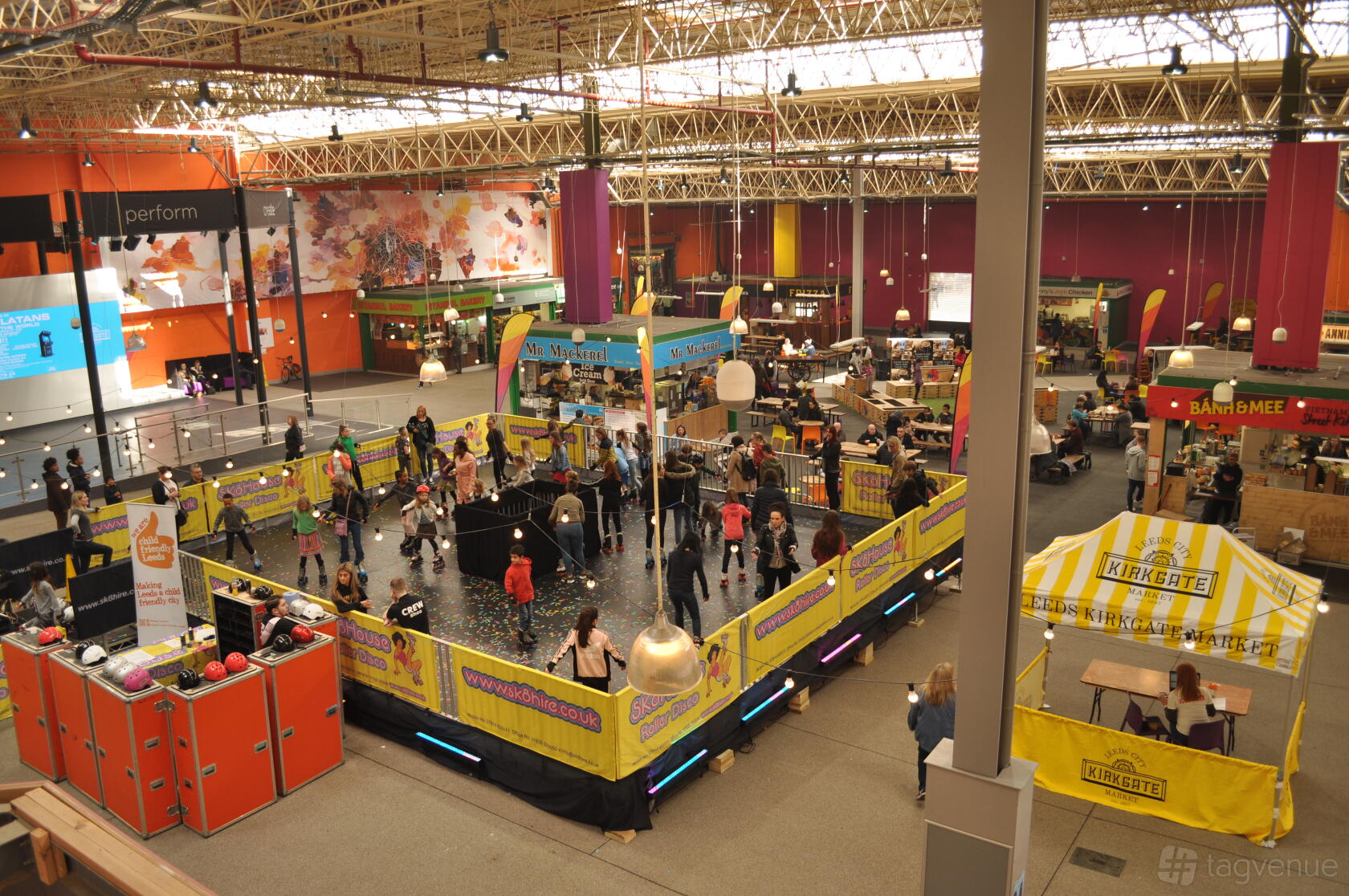 A historic building with high ceilings, exposed metal beams, and a central event area at Leeds Kirkgate Market.