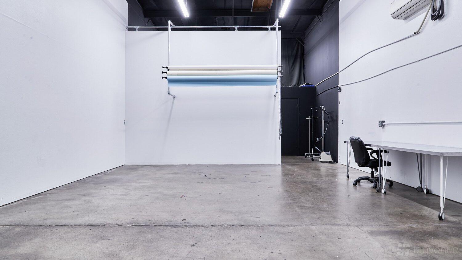 A warehouse studio with polished concrete floors, seamless photography backdrops, and a work desk at RESRC Studios.