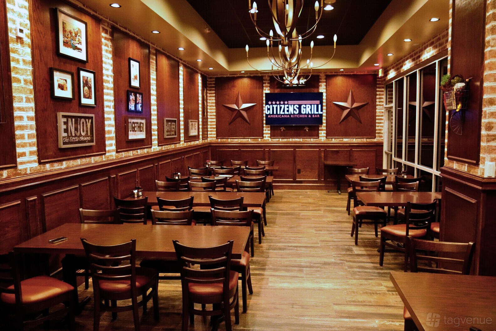 A restaurant dining room with exposed brick walls, wooden tables, and a chandelier at Citizens Grill.