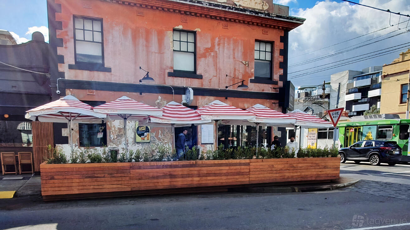 An outdoor bar area with striped umbrellas, wooden planter fencing, and seating at The Quarry Hotel.
