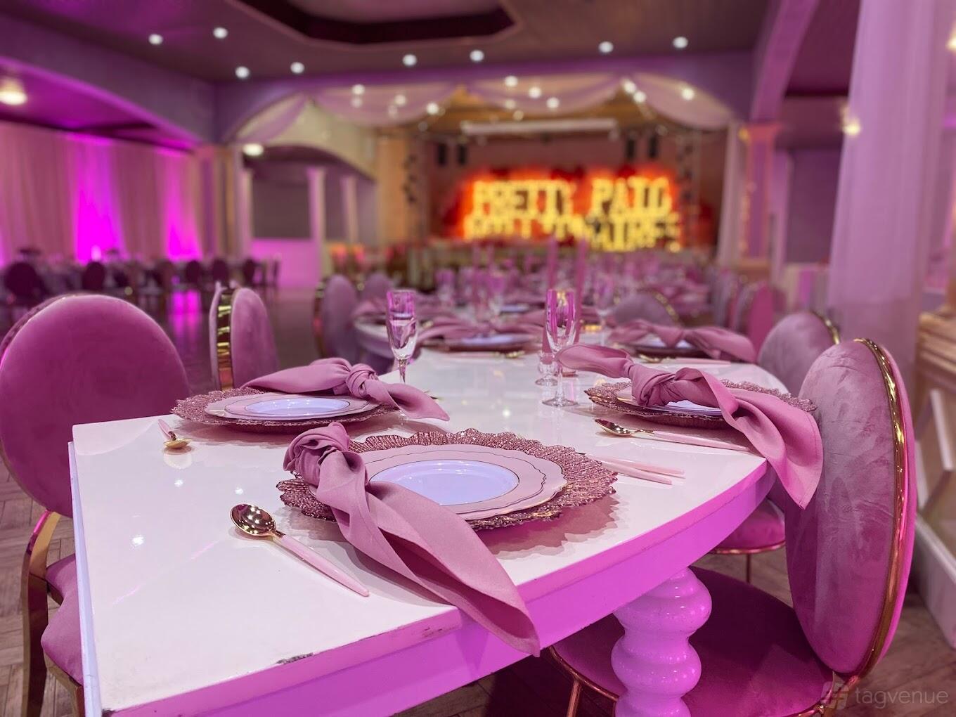A hall with pink upholstered chairs, draped ceiling, and banquet tables set with elegant place settings at Villalpando's Reception Hall.