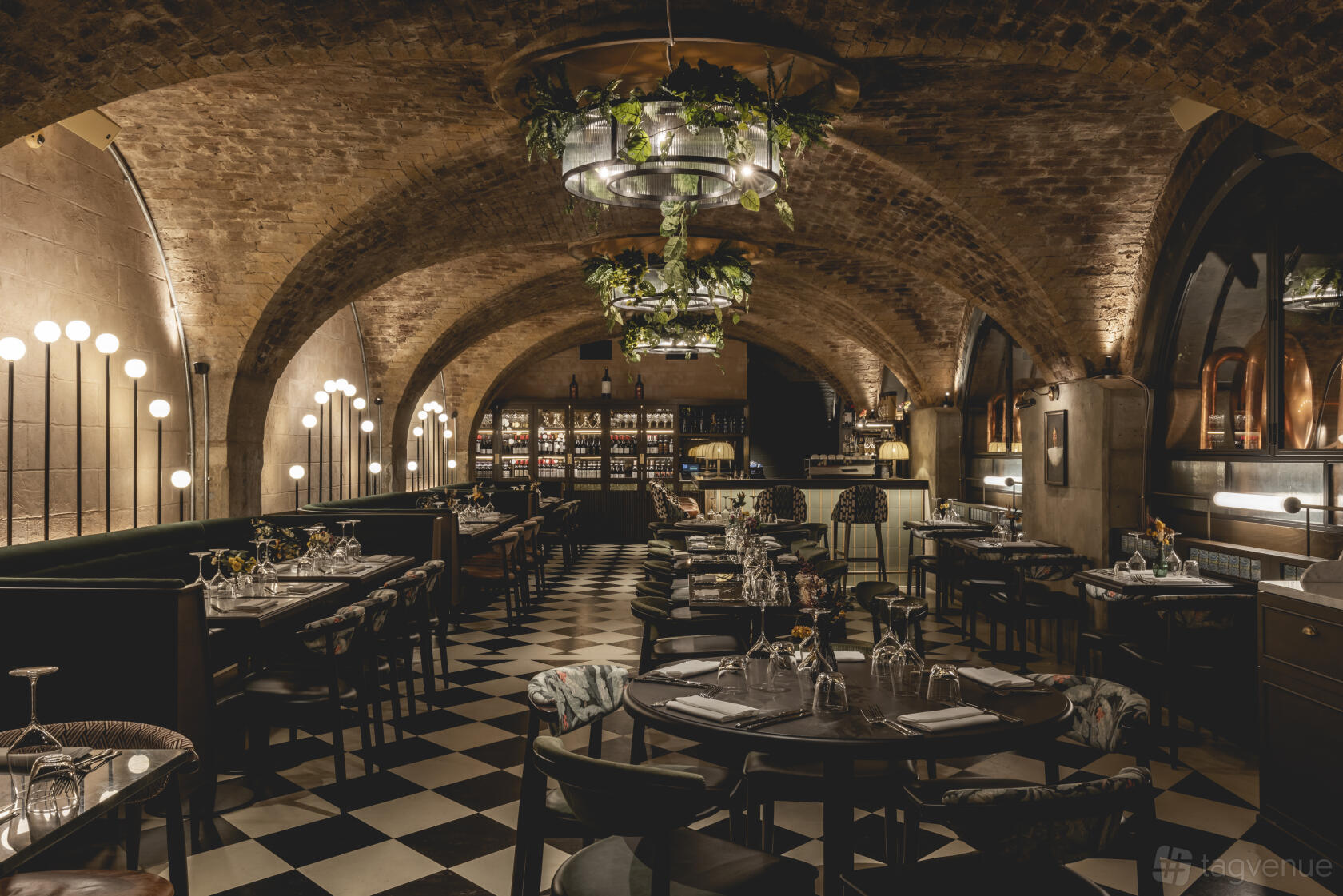 A restaurant with arched brick ceilings, checkered floors, and hanging greenery at The Libertine.