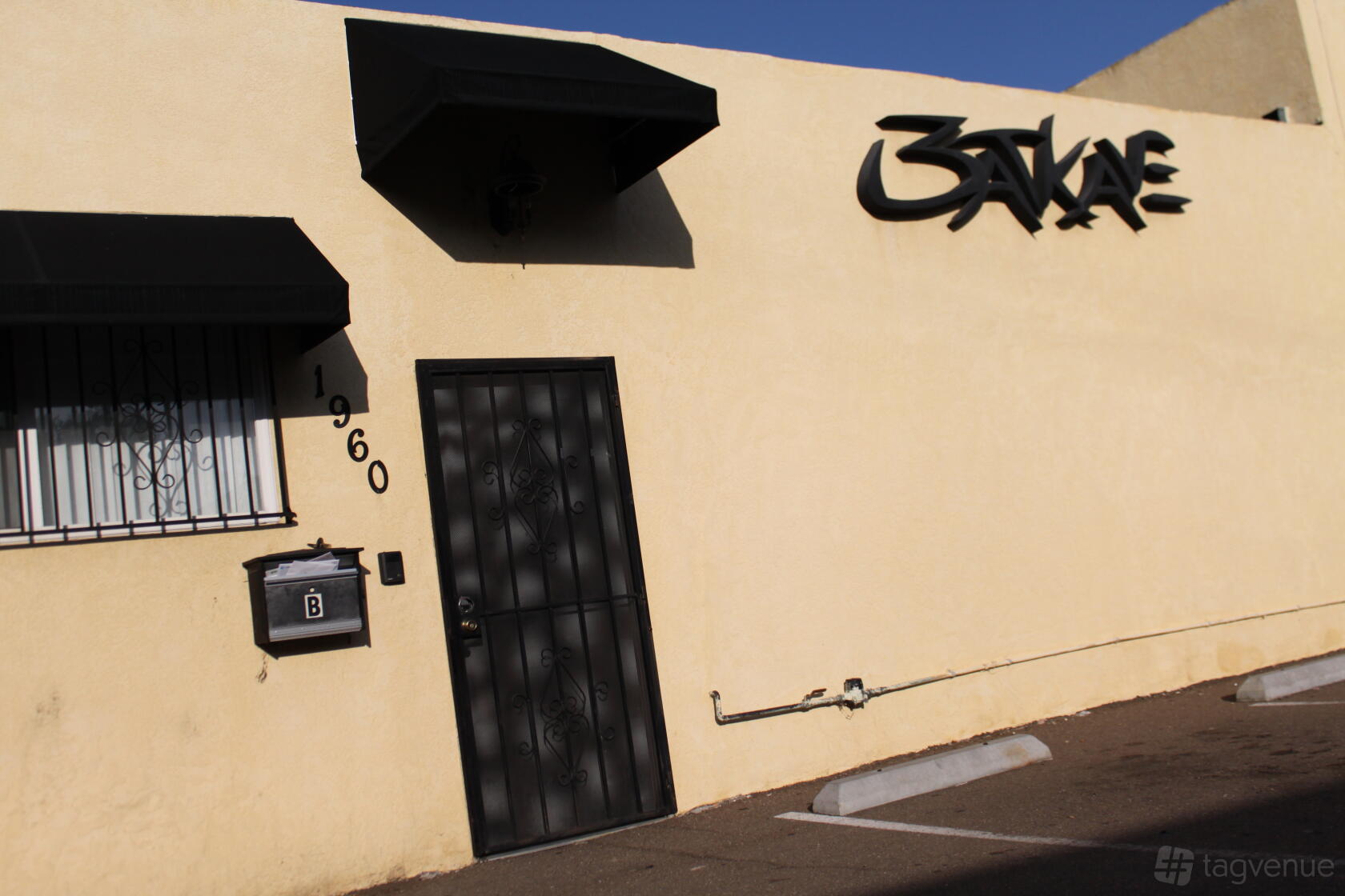 A recording studio with a beige exterior, black metal door, and wall-mounted sign at Hookmaster Studios.