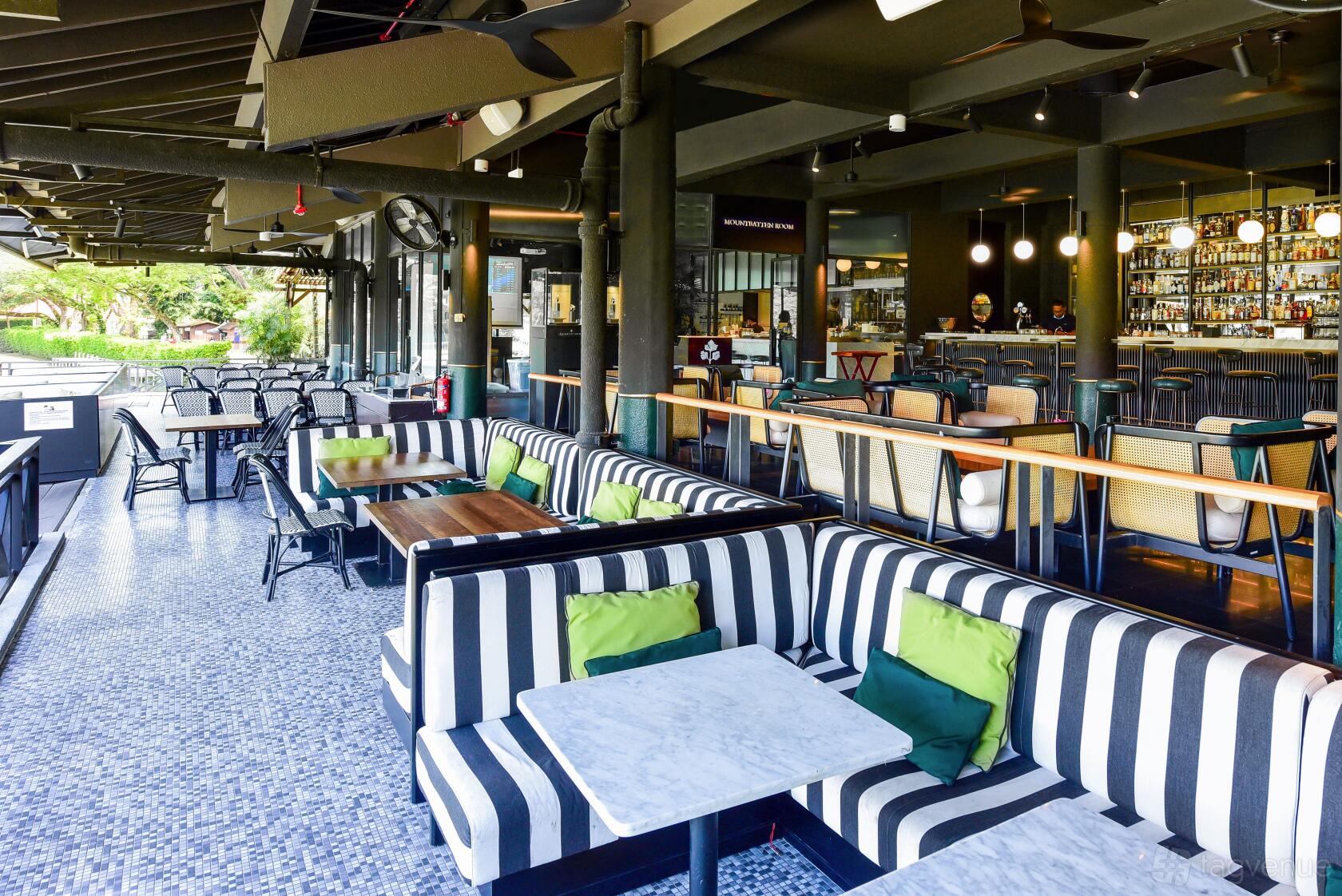A restaurant terrace with striped cushioned seating, marble tables, and open-air views at Coriander Leaf @ Polo Club.