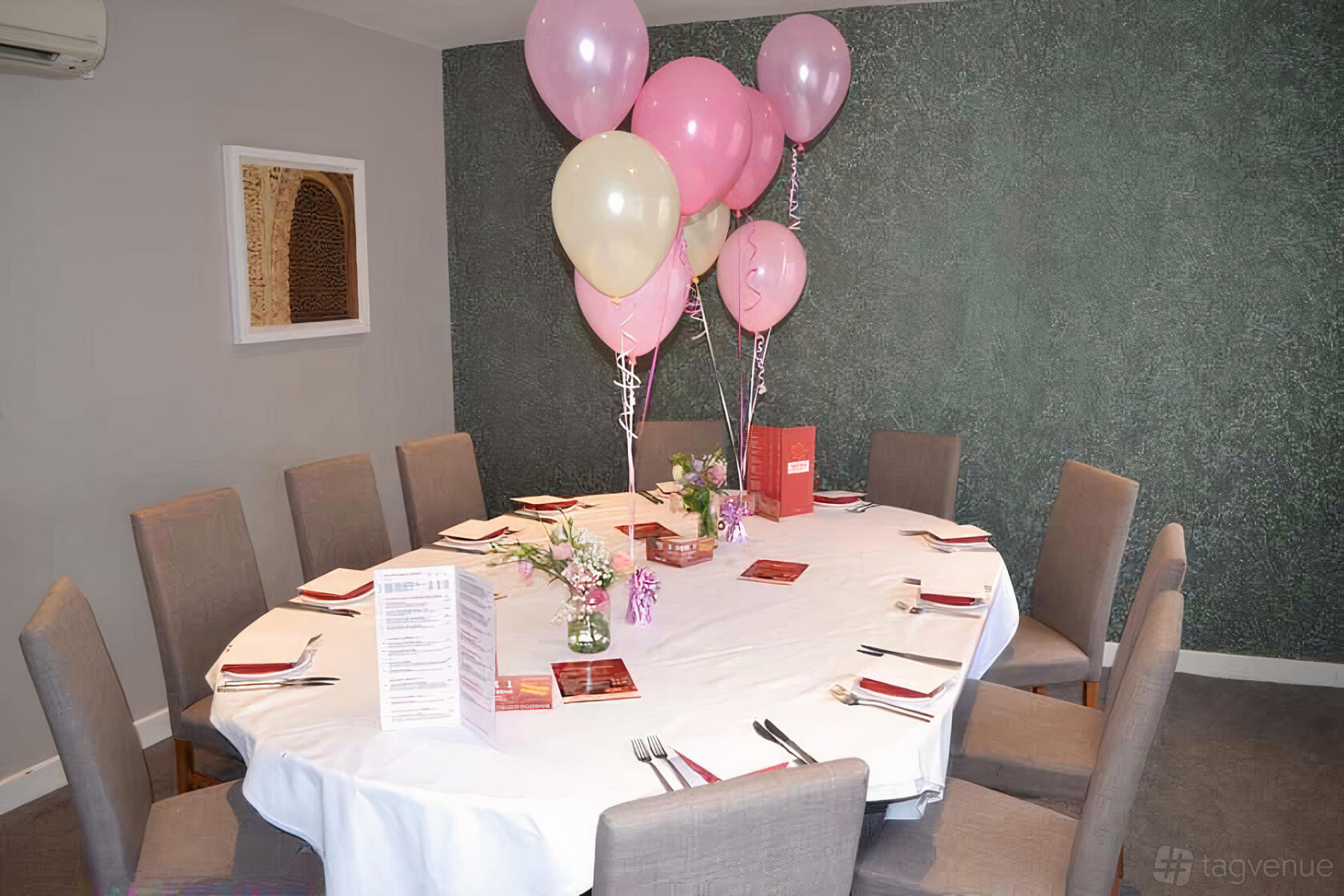 A private function room with a round table, pink and white balloons, and floral centerpieces at Bangla Lounge (Halesowen).