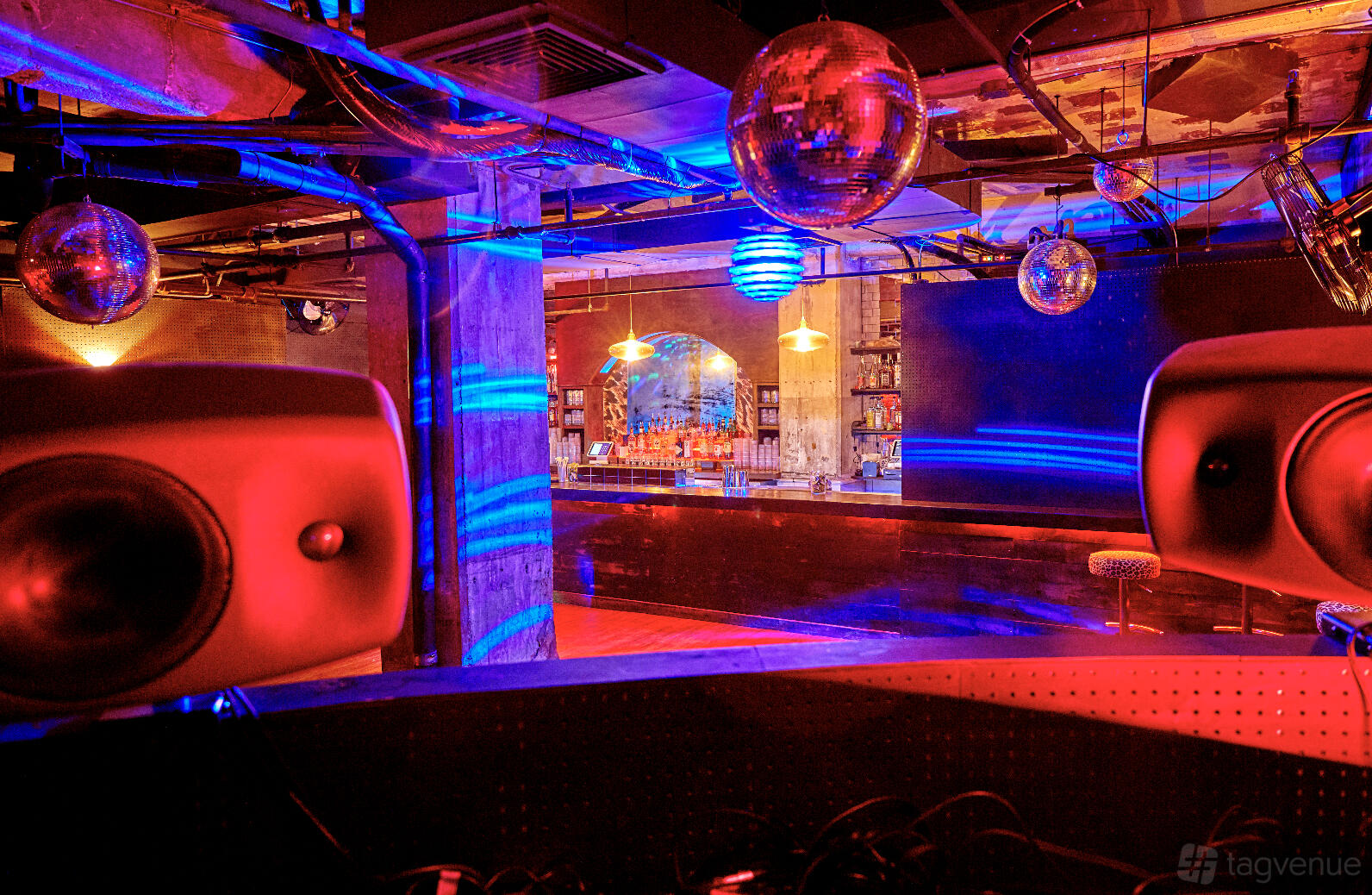 A bar with colorful lighting, disco balls, and a mirrored back bar at Cafe Balearica.