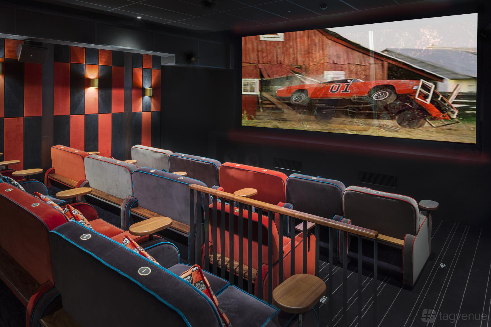 A screening room with velvet armchairs, striped carpet, and a large movie screen at Everyman Newcastle.